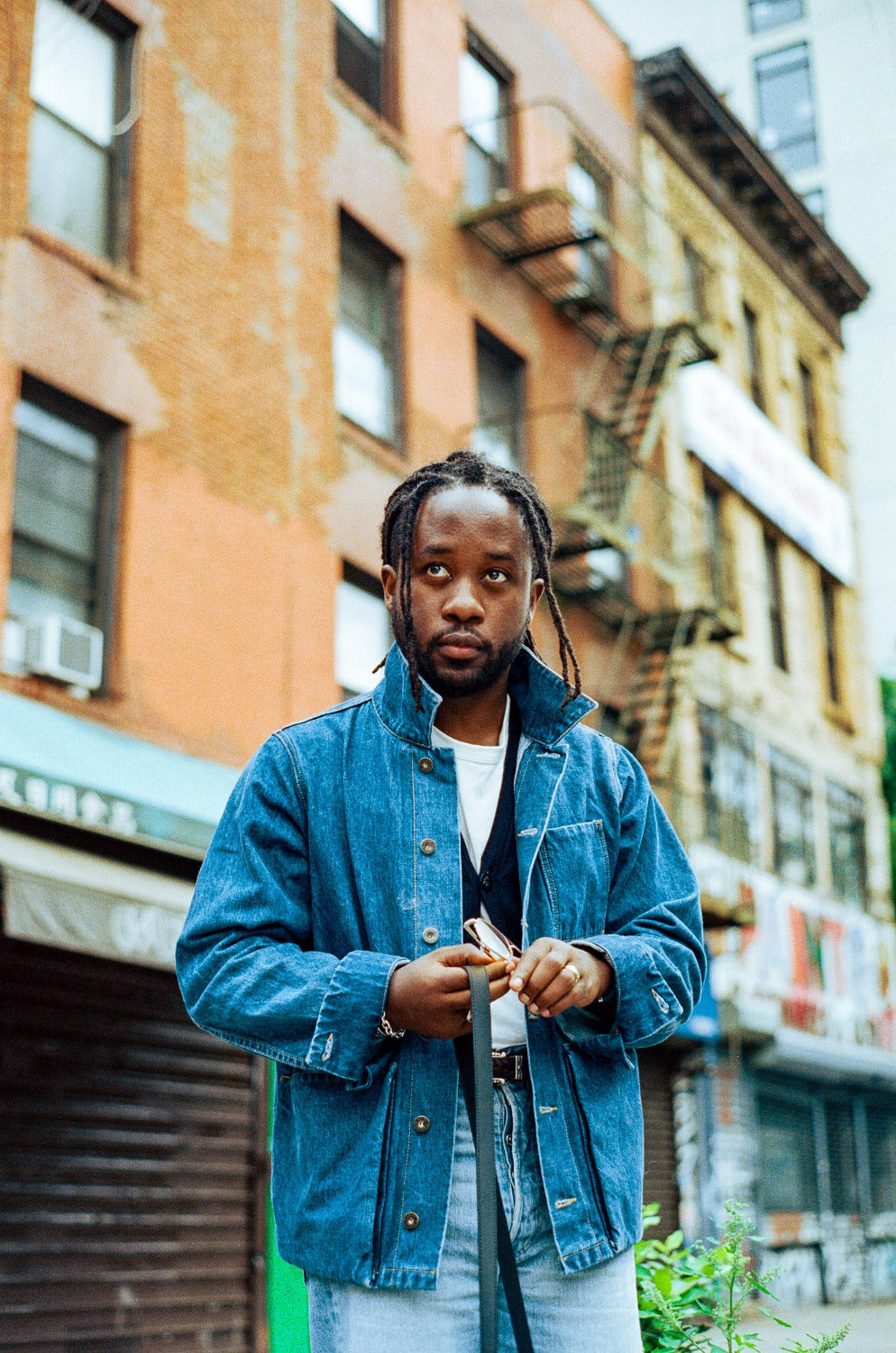 Person wearing a blue denim jacket standing in an urban setting