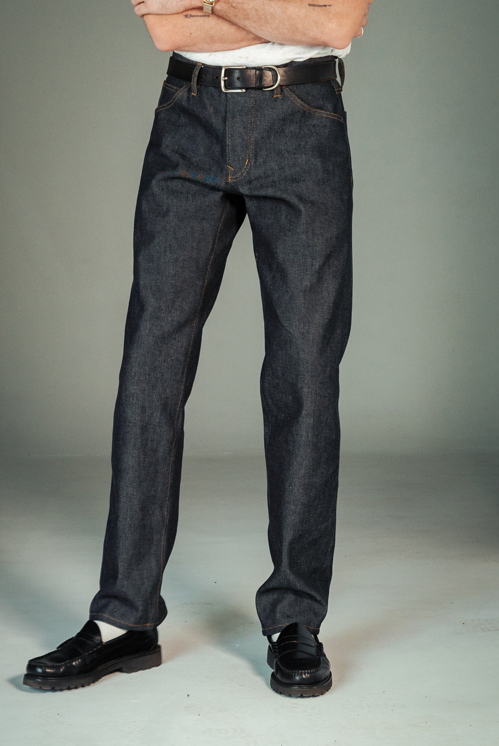 Person wearing dark blue jeans with a plain background