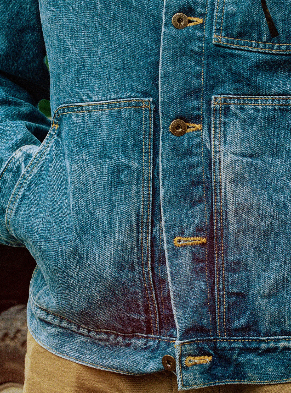 Close-up of a blue denim jacket with buttons and stitching details.
